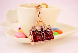 Detailed macro of gold handbag keychain with rhinestones on a ceramic mug edge