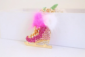Detail of glittery roller skate keychain with pink rhinestones and fluffy pom poms