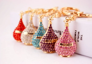 Detailed macro view showing perfume bottle keychains in five different rhinestone colors