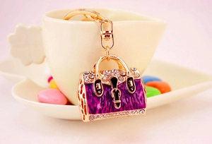 Close-up of purple leopard enamel handbag keychain with crystals on a coffee cup