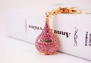 Detail of a gold perfume bottle keychain with pink rhinestones on an open book