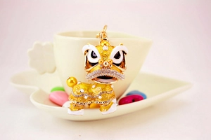 Détail d'un porte-clés lion chinois doré avec strass posé sur une soucoupe de café