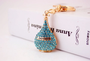 Macro detail of perfume bottle keychain with sky blue rhinestones and gold Parfum engraving