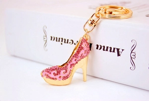 Détail du porte-clés chaussure à talon doré avec strass roses et motifs émaillés