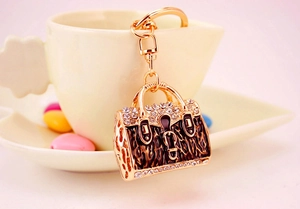 Close-up of golden handbag keychain with brown animal print enamel and shiny rhinestones