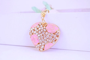 Détail d'un porte-clés cœur avec roses roses et cristaux brillants sur alliage doré