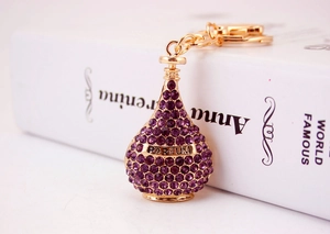 Close-up of golden perfume bottle keychain with purple rhinestones and Parfum text