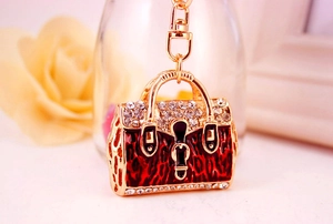 Detail of golden handbag keychain with red leopard print enamel and sparkling rhinestones