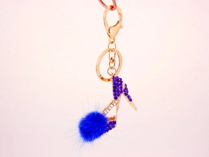 Détail de porte-clés talon haut avec strass bleus, pompon doux et fermoir mousqueton or rose