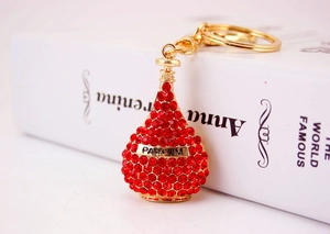 Close-up of red rhinestone-encrusted perfume bottle keychain with golden Parfum plaque