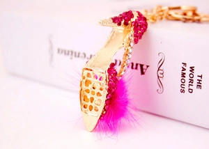 Détail du porte-clés talon haut avec strass rose rouge et pompon doux sur un livre blanc