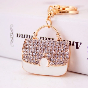 Porte-clés sac à main doré élégant avec strass blancs et émail sur livre blanc