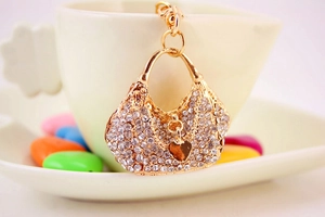 Detail view of a gold handbag keychain with crystal rhinestones and heart charm