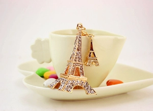 Macro detail of golden Eiffel Tower keychain with sparkling white rhinestones on a tea cup