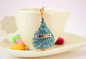Detail of blue rhinestone perfume bottle keychain with PARFUM engraving on a white cup