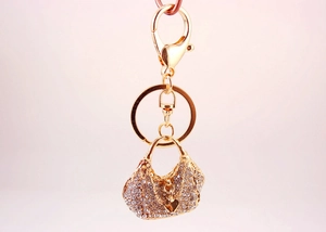 Close-up of golden handbag keychain with sparkling rhinestones and lobster clasp detail