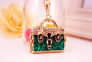 Detailed macro view of a golden handbag keychain with green leopard enamel and sparkling rhinestones