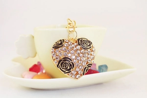 Macro detail of heart-shaped keychain with gold plating, rhinestones and black roses