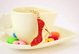 Détail d'un porte-clés escarpin doré avec strass rouges accroché à une tasse en céramique
