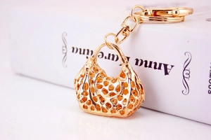 Macro shot of golden handbag-shaped keychain with intricate hollow mesh design