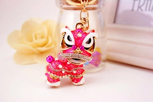 Détail d'un porte-clés lion de danse rose avec strass, émail et finitions dorées