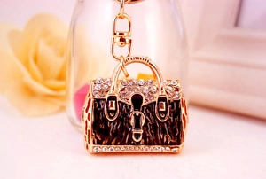 Close-up of leopard print handbag keychain with white rhinestones and golden metal frame