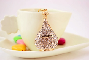 Close-up of golden perfume bottle keychain with white rhinestones and Parfum text