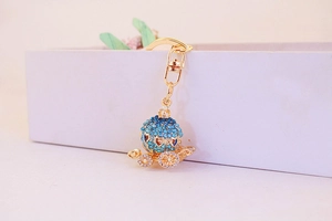 Close-up of golden pumpkin carriage keychain with sparkling blue rhinestones and heart cutouts
