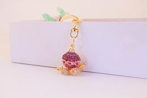 Close-up of golden pumpkin carriage keychain with purple gradient rhinestones and crystals