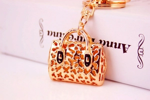 Detailed close-up of a golden hollow leopard print handbag keychain with black enamel drips