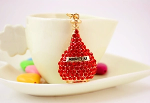 Close-up of golden perfume bottle keychain with red rhinestones and PARFUM text