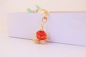 Detailed view of a golden pumpkin carriage keychain with red and white rhinestones