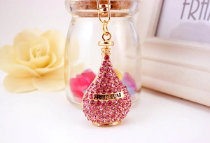 Macro detail of golden perfume bottle keychain with pink rhinestones and Parfum engraving