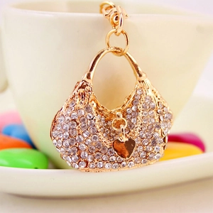 Sparkling rhinestone handbag keychain with golden alloy heart pendant on a white cup