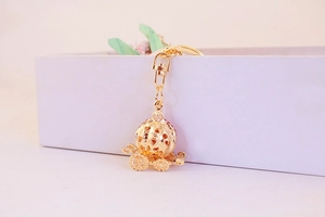 Detail of golden pumpkin carriage keychain with hollow heart design and red rhinestones