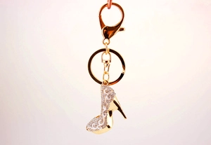 Détail d'un porte-clés escarpin avec finition dorée et motif en émail blanc serti de strass