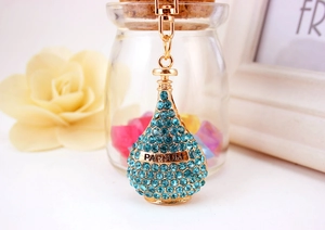 Detailed macro view of perfume bottle keychain with blue crystals and PARFUM engraving