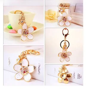 Macro detail of enamel daisy keychain with rhinestones and gold lobster clasp for bags
