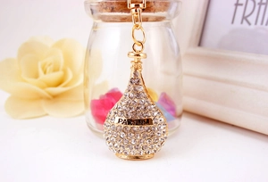 Macro detail of gold perfume bottle keychain with sparkling rhinestones and Parfum text