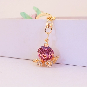 Charming golden pumpkin carriage keychain with purple and white rhinestones and heart design