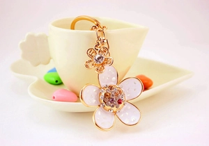 Detailed close-up of a daisy flower keychain with rhinestones hanging on a coffee cup