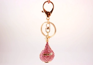 Macro detail of golden perfume bottle keychain with pink rhinestones and Parfum label