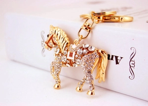 Close-up of golden horse keychain with sparkling rhinestones on vintage book