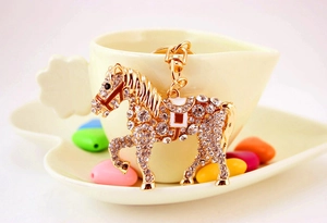 Detail of a sparkling horse keychain with crystals and gold finish on a soft background