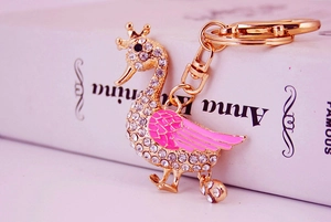 Close-up of golden swan keychain with pink enamel wings and white sparkling rhinestones