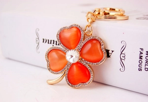 Macro shot of orange heart opal clover keychain with sparkling crystals on gold metal