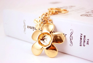 Macro detail of a golden five-petal flower keychain pendant on a white book surface