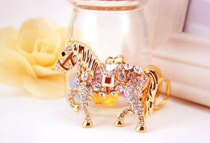 Close-up of golden horse keychain with sparkling rhinestones and white enamel accents