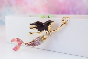 Detailed macro view of mermaid pendant with purple rhinestones and gold alloy frame