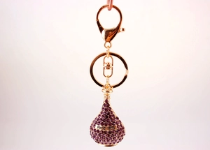Detail of a gold parfum bottle keychain with purple crystals and fine engraving